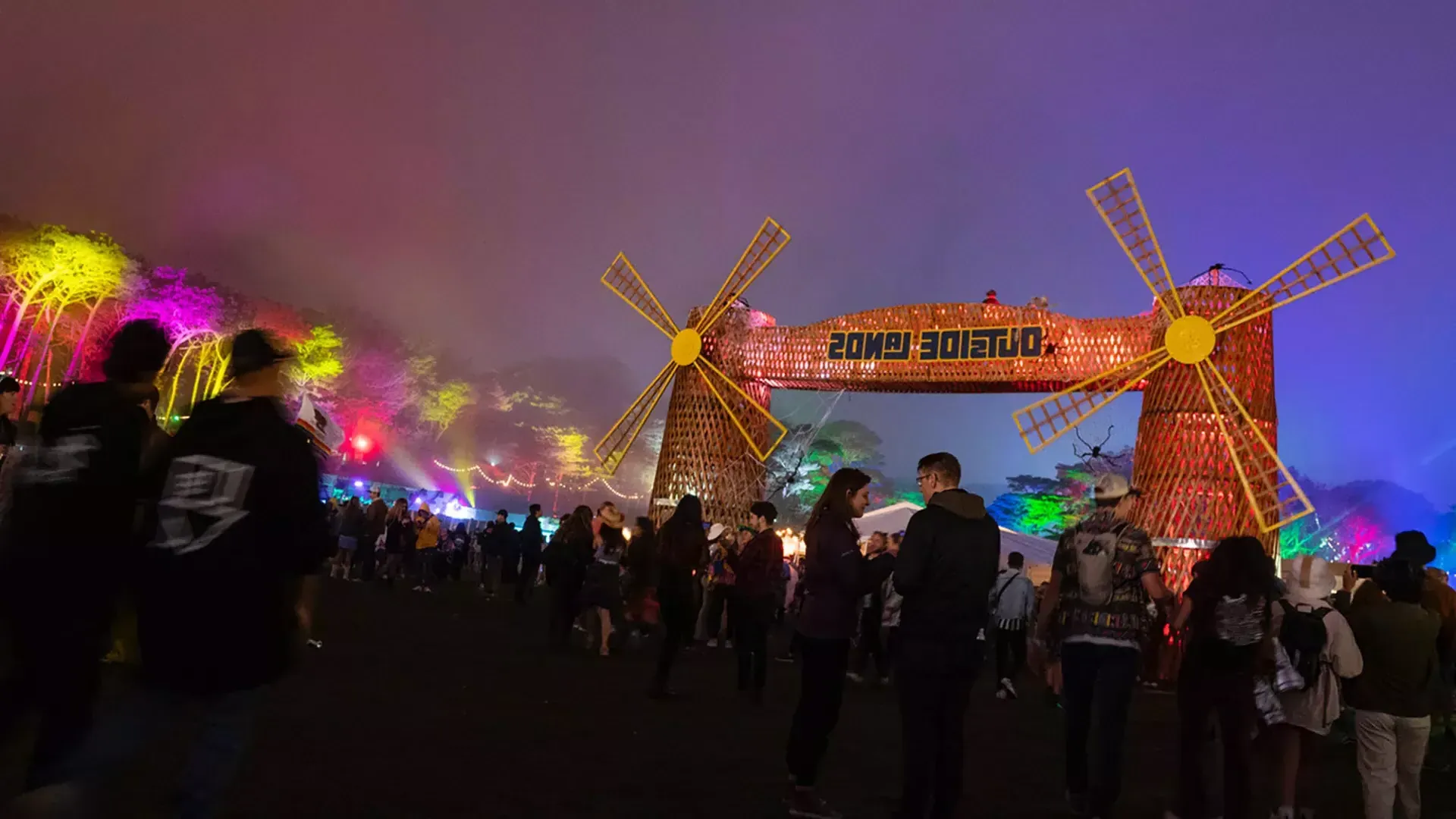 Una multitud de asistentes al 节日 son fotografiados de noche en medio de luces de neón en el 节日 de 音乐 Lands框架之外 在贝博体彩app.