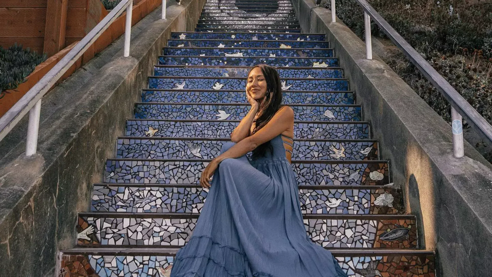 A woman poses sitting on 的 16th Avenue tiled stairs in 的 Sunset neighborhood of San Francisco.