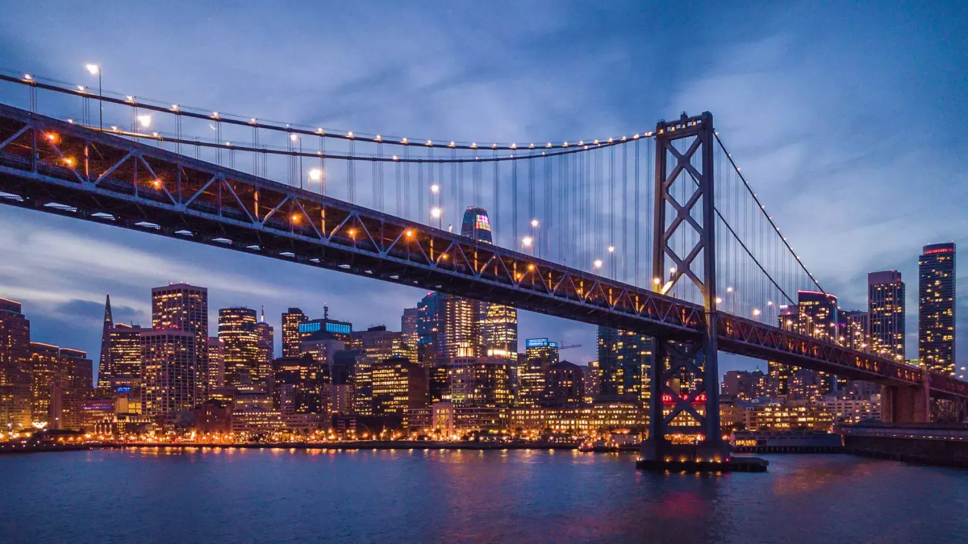 Le Bay Bridge et le front de mer d'Embarcardero sont illuminés la nuit.