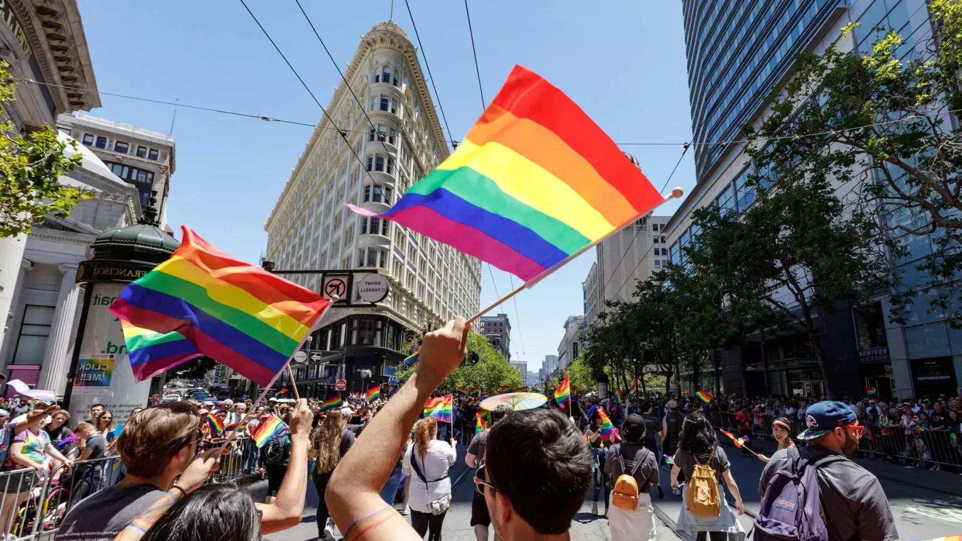 Le persone che camminano nella parata del Pride di San Francisco sventolano bandiere arcobaleno.