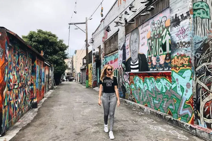 A woman walks through an alley in 教会区 that is covered with murals 和 artwork. San Francisco, California.