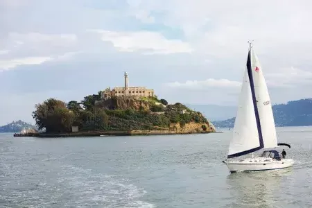 sailboat passes in front of Alcatraz Island in San Francisco.