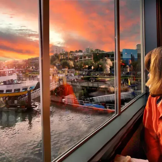 Woman looking out the window of Fog Harbor restaurant towards the wharf